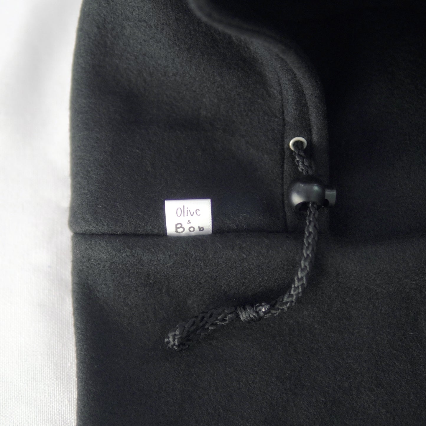 A handmade Noir Hoodeanie in solid black, displayed to show its soft, cozy fabric and new adjustable face panel feature. The design allows the hood to be pulled up snugly over the nose for added warmth and comfort, blending functionality with minimalist streetwear style.