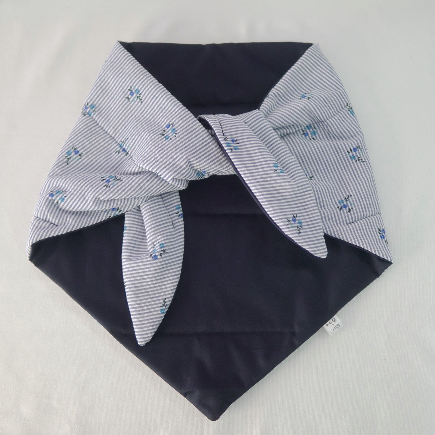 Reversible quilted shawl with a dark floral cotton print and water-resistant black lining, perfect for elegant layering and cool weather style.