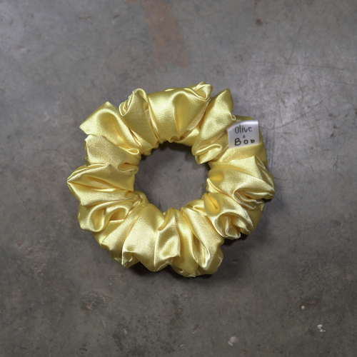 Small yellow satin scrunchie with a smooth satin sheen, mini hair accessory for ponytails and half-up styles.