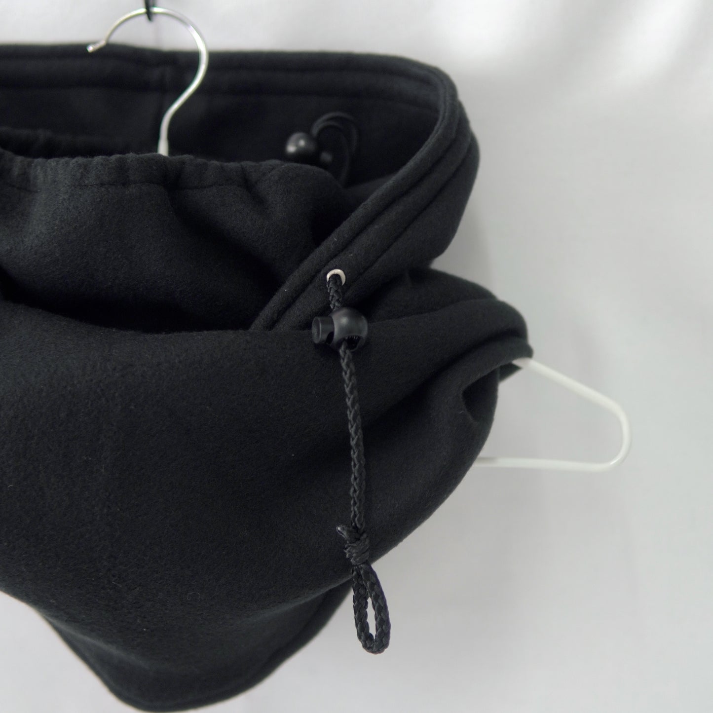 A handmade Noir Hoodeanie in solid black, displayed to show its soft, cozy fabric and new adjustable face panel feature. The design allows the hood to be pulled up snugly over the nose for added warmth and comfort, blending functionality with minimalist streetwear style.