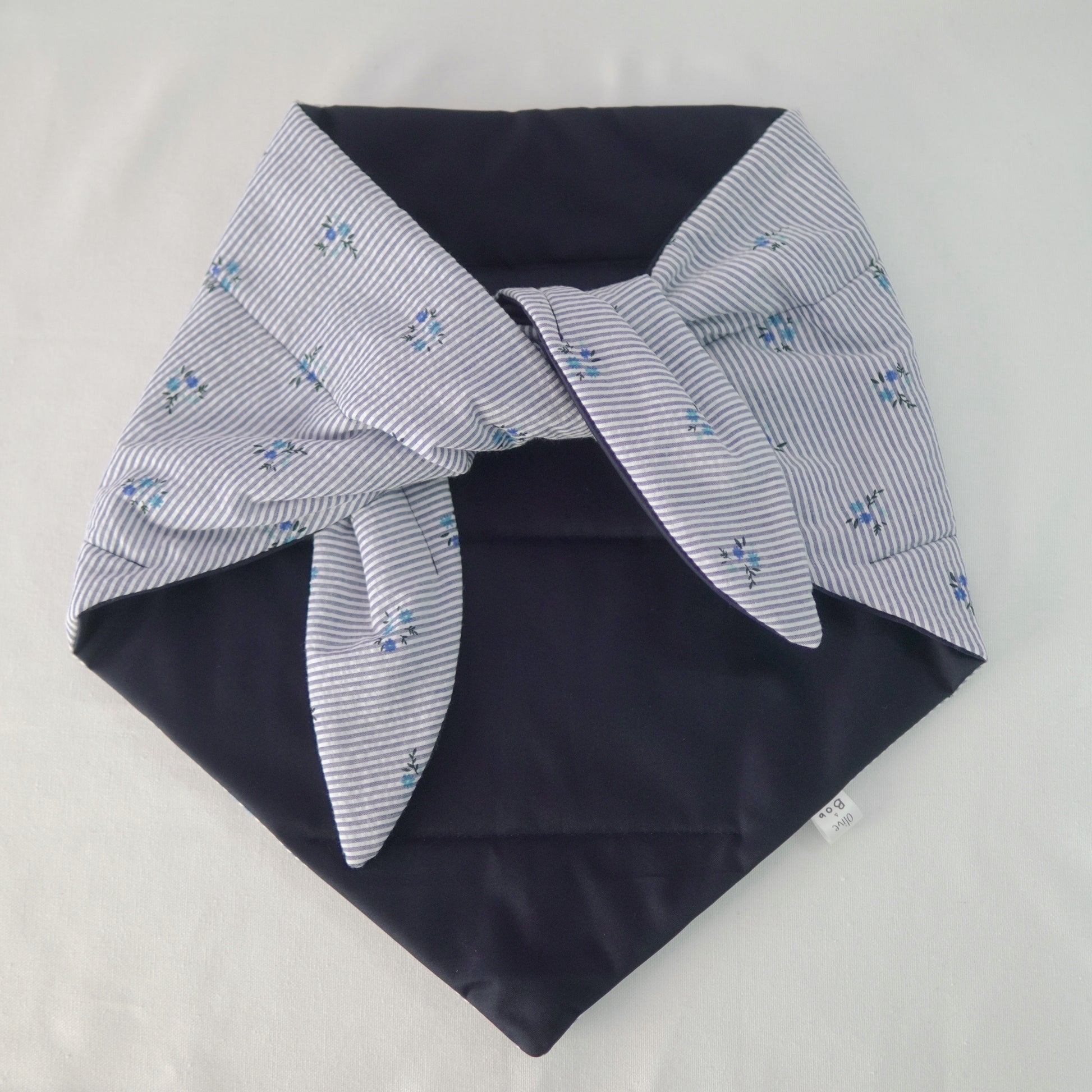 Reversible quilted shawl with a dark floral cotton print and water-resistant black lining, perfect for elegant layering and cool weather style.